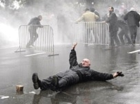 An opposition supporter falls on the street as police disperse protesters in Tbilisi (AFP)