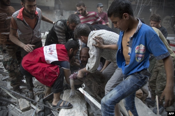 Syrians surround a man as he cries over the body of his child after she was pulled from the rubble of a building following air strikes by government forces in the rebel-held neighborhood of Al-Shaar in Aleppo on September 27.