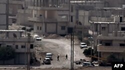 Two members of the Kurdish force known as the People's Protection Units (YPK) walk along a street in a western district of the Syrian town of Kobani on October 13.