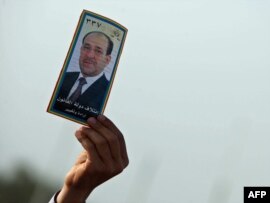 A man holds up an election pamphlet of Prime Minister Nuri al-Maliki during a speech in Karbala.