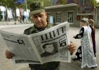 A Tajik military officer reads a newspaper that features the incumbent on Page One (AFP)