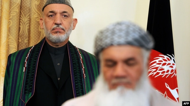 Water and Energy Minister Mohammad Ismail Khan (front) signs a document as Afghan President Hamid Karzai looks on at the presidential palace in Kabul in 2010.