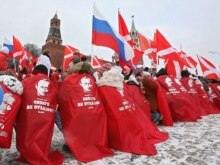 Russia -- Young people covered in red and decorated with Vladimir Putin's portraits take part in rally of pro-presidential youth movement