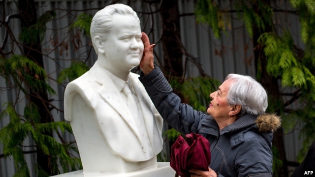 A woman touches the bust at the grave of late Yugoslav President Slobodan Milosevic in the town of Pozarevac, Serbia.