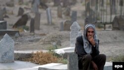 An elderly Afghan man sits at a grave in a graveyard of Afghan casualties of the Soviet war.