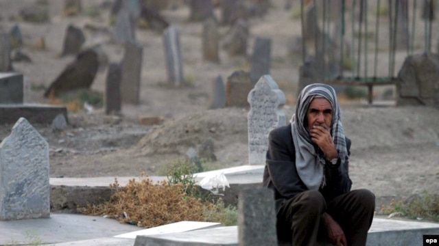 An elderly Afghan man sits at a grave in a graveyard of Afghan casualties of the Soviet war.
