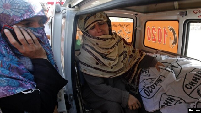Rukhsana Bibi (center) weeps in an ambulance outside Jinnah Hospital in Karachi on December 18, next to the body of her slain daughter Madiha, who worked for an antipolio campaign.