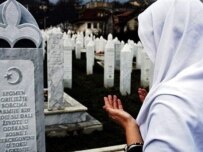A Bosnian woman prays at the graves of Srebrenica victims on February 25 (AFP)