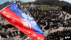 The flag of the so-called "Donetsk People's Republic" flies above a barricade and a crowd gathered in front of the Donetsk regional administration building, which is being held by pro-Russian militants.