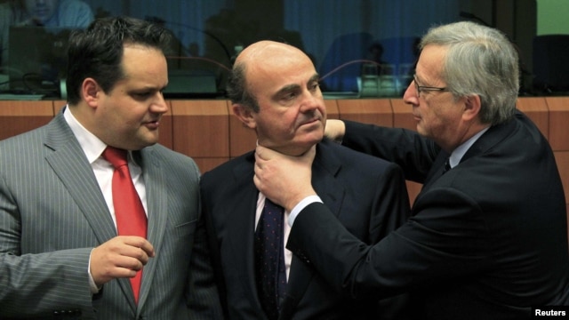 Spanish Economy Minister Luis de Guindos (center) jokes with Luxembourg Prime Minister and then-Eurogroup Chairman Jean-Claude Juncker (right) at a meeting in March 2012.