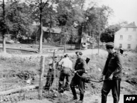 Чыгыш Германиянын чек арачылары тикенек зымдарды тартууда. Кийин тикенектүү зым коргонду бетон дубал алмаштырат. 1957-ж.