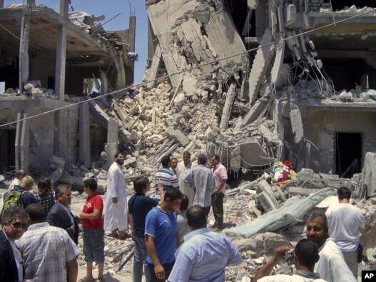 Members of the media and others examine the remains of a damaged residential building in Tripoli on June 19, 2011