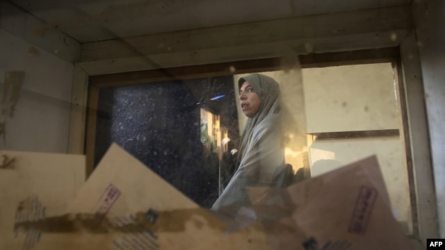 A picture taken through a ballot box shows an Egyptian woman casting her vote in the first-round runoff at a polling station in the Cairo neighborhood of Al-Manial on December 5.