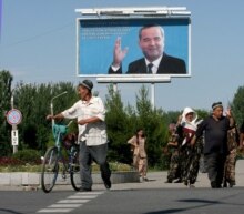 Uzbekistan/Andijon - Local residents cross a road in Andijon under the portrait of Uzbek President Islam Karimov, 17 May 2005.