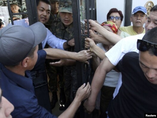 Activists block an entrance to the seat of the Kyrgyz parliament during a protest rally in Bishkek on August 15 over the treatment of former Defense Minister Vaktybek Kalyev.