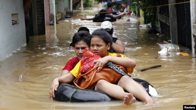 A woman sits on an inflatable rubber tube as she is evacuated from her flooded housing complex in Jakarta on January 16. 