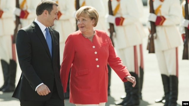 Moldovan Prime Minister Vlad Filat (left) walks with German Chancellor Angela Merkel during a welcoming ceremony at Chisinau airport.