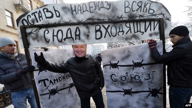 A young activist wearing a mask of Ukrainian President Viktor Yanukovych invites passersby to go through a symbolic gate with the words "Customs Union" and "Abandon Hope, All Ye Who Enter Here," during a protest in front of the presidential office in Kyiv in December.