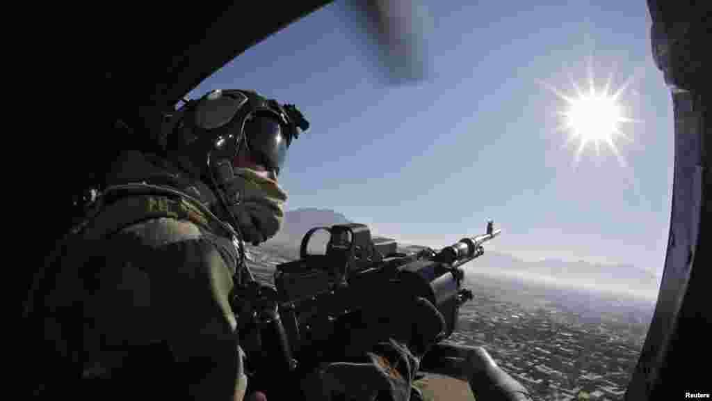 A French gunner remains alert and ready aboard a helicopter during a flight above Kapisa Valley, Afghanistan.