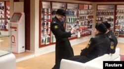 A Russian cadet uses a mobile phone to photograph other cadets in a phone shop in St. Petersburg.