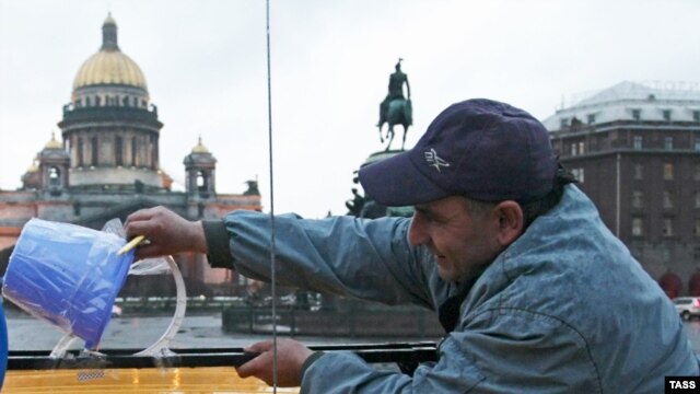 Russia -- A protester taps a fake "blue light", a blue bucket turned upside-down, to a roof of his car in St. Petersburg, 22Apr2010