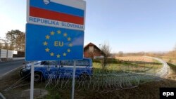 A Slovenian police van is in attendance at a barbed-wire barrier behind a Republic of Slovenia and European Union sign in the village of Rigonce, on Slovenia's border with Croatia on November 12.