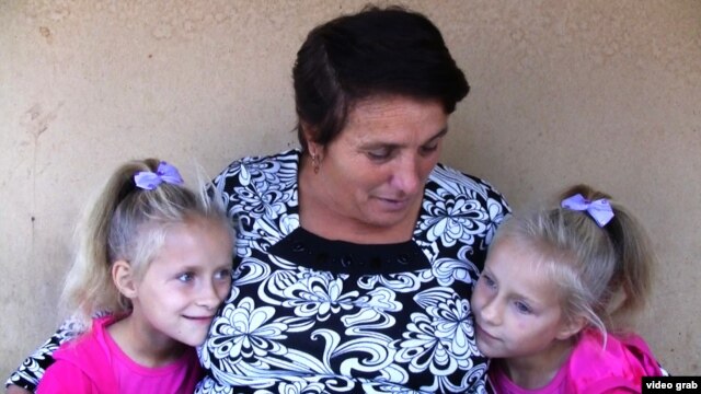 Maria Barbanou (center) is raising two of her granddaughters while their mother, Maria’s daughter, is working in Italy. 