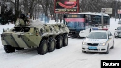 A Ukrainian armored personnel carrier tows a trolleybus behind it on a road covered with snow in Kyiv. (file photo)