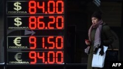 A woman walks past a board listing foreign currency rates against the Russian ruble in Moscow on January 21.