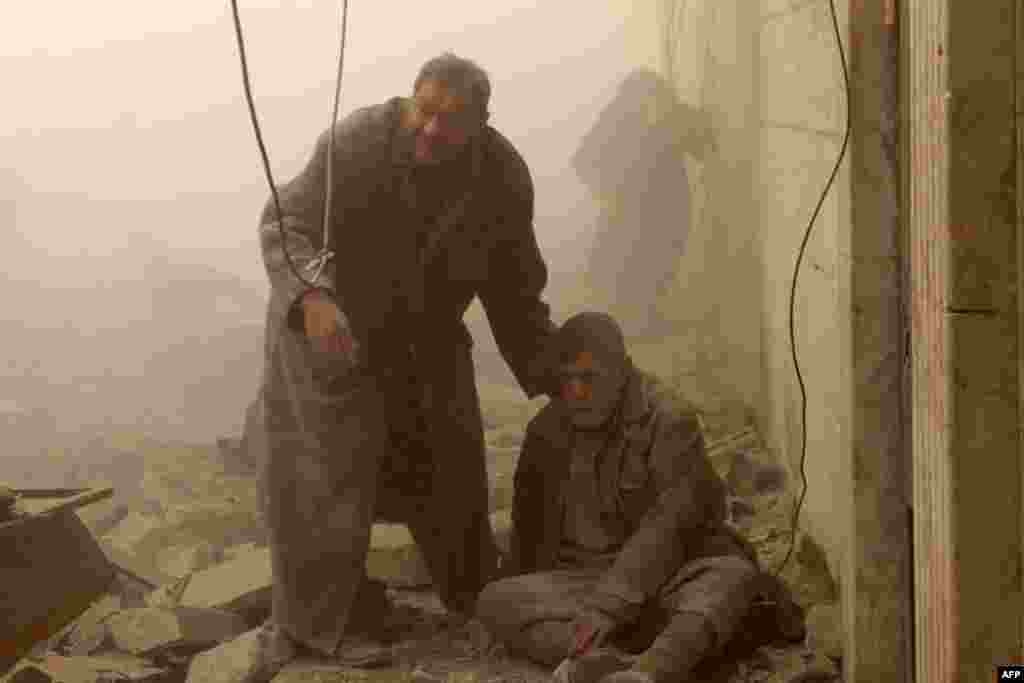 A man helps an injured person following an air strike in Aleppo's in Syria on December 17. (AFP/Mohammed Al-Khatieb)