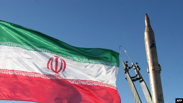 The national flag flutters next to a ground-to-ground Sejil missile before being launched at an undisclosed location in Iran.