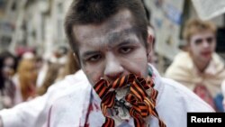 A demonstrator dressed as a zombie protests in Ukraine against Russian propaganda by stuffing his mouth with newsprint and St. George's ribbons, a symbol used by pro-Russia rebels in the east.