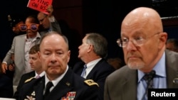 U.S. Director of National Intelligence James Clapper (right) and General Keith Alexander, director of the National Security Agency, testify at a House Intelligence Committee hearing on October 29 as a protester is ejected from the room.