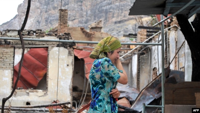 An ethnic Uzbek woman cries as she passes by a burned-out house in Osh on June 24.
