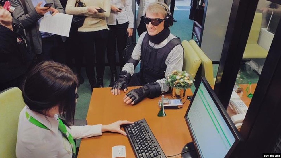 Dressed in an outfit vaguely reminiscent of Robocop, the former economy and trade minister glided through the flagship Sberbank branch in Moscow wearing special glasses, earmuffs, and body padding designed to impair his sight and hearing, and restrict his movement.