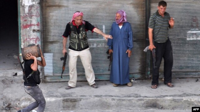 A Syrian rebel carries a homemade explosive device as others stand back to let him pass during fighting in Aleppo, which could have a crucial impact on the course of events in Syria. 