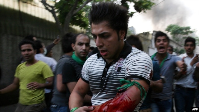 Iranians react as a protestor is wounded at the opposition rally in Tehran on June 15