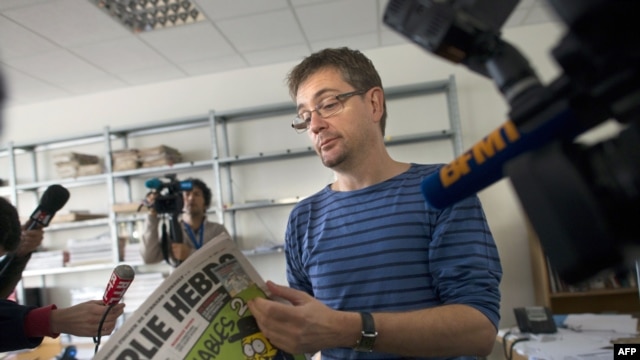 The publisher of the French satirical weekly "Charlie Hebdo," known only as Charb, answers questions posed by journalists as he holds the latest edition of the magazine in Paris on September 19.