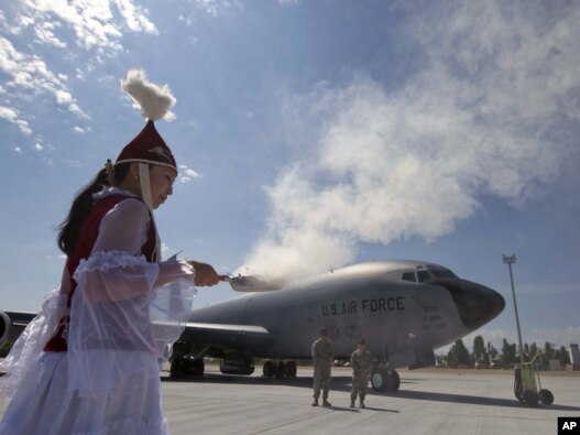 A woman performs a traditional ritual during a ceremony to open a new large aircraft ramp at the Manas Army airbase near Bishkek. 