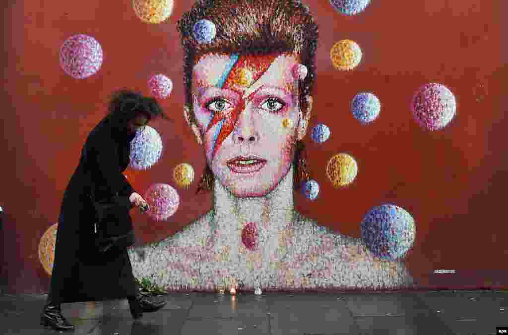 A fan sprinkles black pepper at a mural of British singer David Bowie in his hometown of Brixton, London, on January 11, after the announcement of the singer's death from cancer at the age of 69. (epa/Andy Rain) 