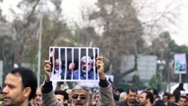 A government supporter holds a poster with a picture of opposition leaders Mehdi Karrubi (left) and Mir Hossein Musavi during a demonstration in Tehran on December 30.
