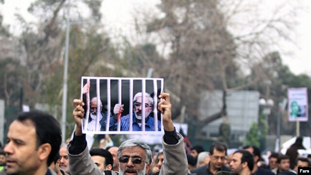 A government supporter holds a poster with a picture of opposition leaders Mehdi Karrubi (left) and Mir Hossein Musavi during a demonstration in Tehran on December 30.
