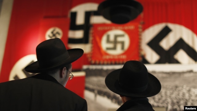 Ultra-Orthodox Jewish visitors look at a display of Nazi flags at Yad Vashem's Holocaust History Museum in Jerusalem.