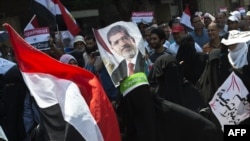 Supporters of the Muslim Brotherhood and ousted Egyptian President Muhammad Morsi hold his picture as they march toward Cairo University to demand his reinstatement on July 19.