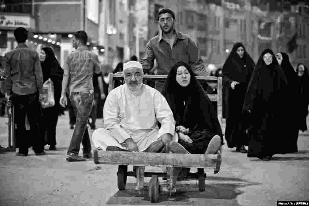 A father and daughter with limited mobility receive assistance while visiting holy Shi'ite sites in Karbala.