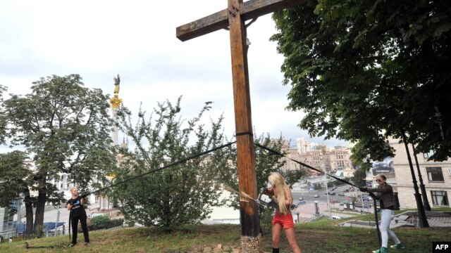 Femen activists use a chainsaw to cut down an Orthodox cross in Kyiv.