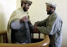 Afghanistan -- Justice -- An Afghan intelligence policeman (R) opens the handcuffs on Reza Khan in a Kabul court, 20 Nov. 2004