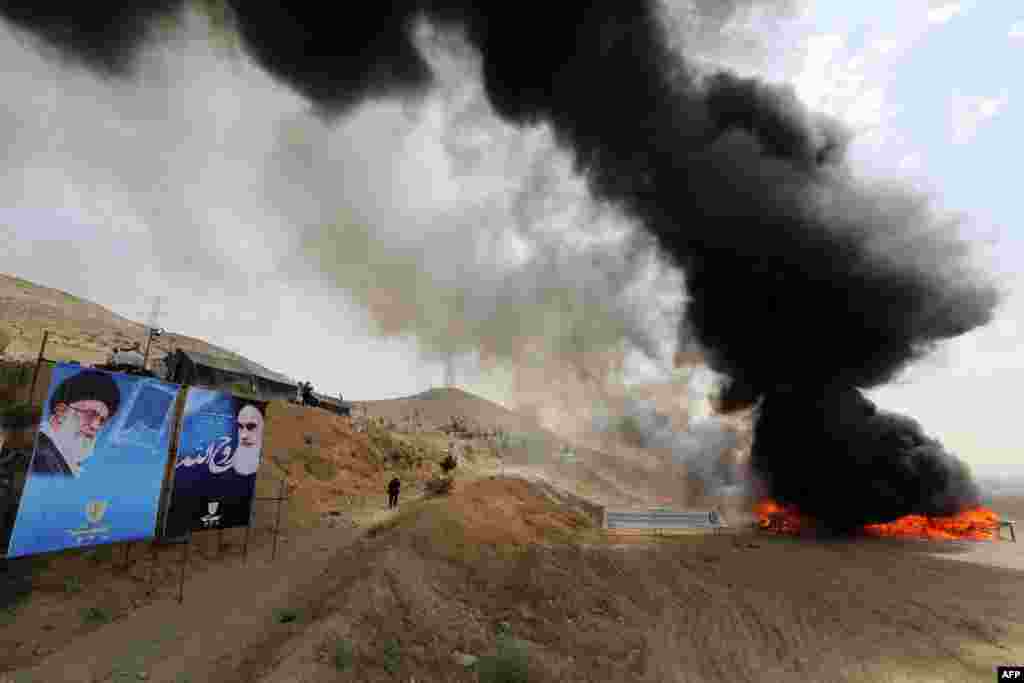 Fifty tons of drugs seized in recent months burn next to portraits of Iran's Supreme Leader Ayatollah Ali Khamenei (left) and the founder of the Islamic republic, Ayatollah Ruhollah Khomeini, in eastern Tehran on June 26. (AFP/Atta Kenare)