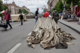 Майдан белсенділері алаңнан жинап алынған шатырды әкетіп барады. Киев, 28 мамыр 2014 жыл.