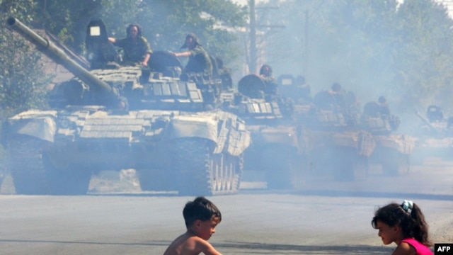 GEORGIA -- Russian tanks move along a street as children play with a toy truck in Tskhinvali, the capital of South Ossetia, 30Aug2008. 